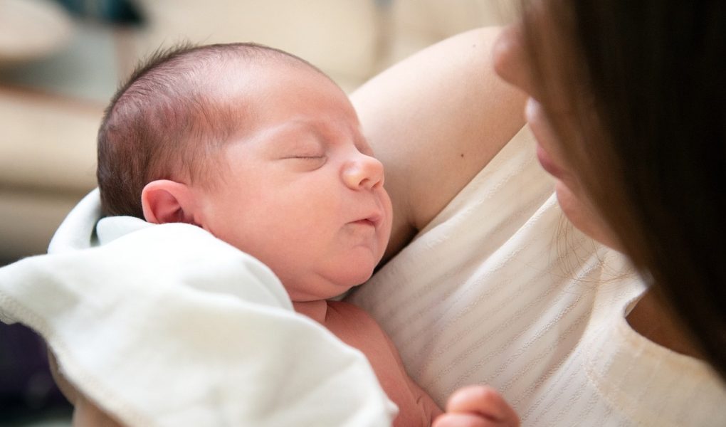 Annesinin kucağında uyuyan yeni doğmuş bebek