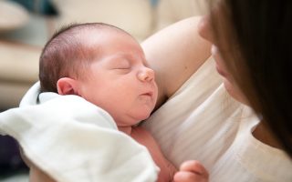Annesinin kucağında uyuyan yeni doğmuş bebek