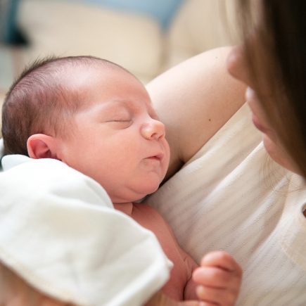 Annesinin kucağında uyuyan yeni doğmuş bebek