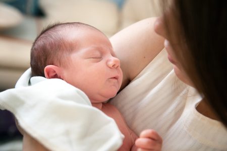 Annesinin kucağında uyuyan yeni doğmuş bebek